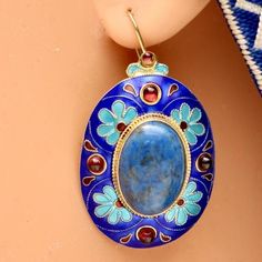 This reproduction of the popular Renaissance pendant, enameled in a floral motif, showcases a lapis stone surrounded by garnets. Handcrafted vermeil (24k gold over sterling silver). Garnet accented french-backs for pierced ears, 1 3/4" tall. Ceremonial Blue Meenakari Jewelry, Blue Gemstone Jewelry For Festivals, Traditional Gold Jewelry With Cabochon, Traditional Gold Jewelry With Oval Cabochon, Blue Oval Cabochon Earrings For Gift, Blue Oval Cabochon Earrings As Gift, Blue Inlay Earrings For Gift, Blue Inlay Earrings For Gifts, Antique Blue Jewelry For Ceremonial Occasions