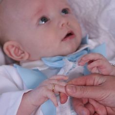 a baby is being held by someone's hand while wearing a blue bow tie