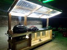 an outdoor bbq grill is lit up at night with lights on the roof and side walls