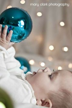 a baby laying on its back playing with a blue ornament in it's mouth