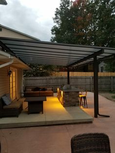 an outdoor patio with furniture and lighting on the side of it, next to a backyard fire pit