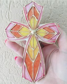 a hand holding a stained glass cross in it's left hand, with white background