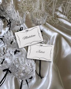 two place cards sitting on top of crystal vases