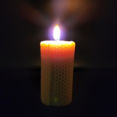 a lit candle in the dark with some light coming from it's top and bottom