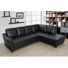 a black leather sectional sofa sitting in front of a book shelf filled with books and framed pictures