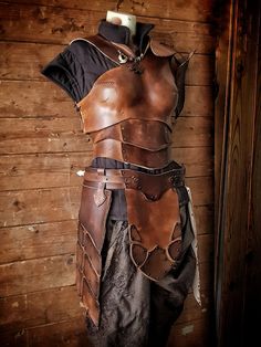 a brown leather outfit hanging on a wooden wall