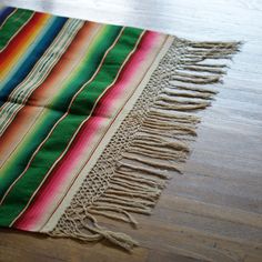 a multicolored blanket laying on top of a wooden floor