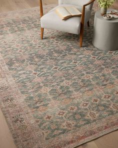 an area rug with a chair and table in the middle, next to a potted plant