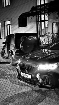 black and white photograph of cars parked in front of a building