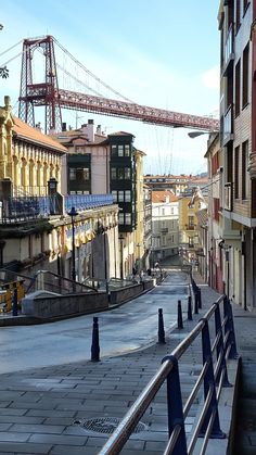 an empty street with buildings and a bridge in the background