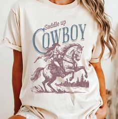 Embrace the spirit of the Wild West with our Cowgirl Western Aesthetic T-shirt! Perfect for every cowgirl at heart, this stylish and comfortable tee brings a touch of rustic charm to your wardrobe. Whether you're headed to a rodeo, country music festival, or just want to stay rowdy on a casual day out, this shirt has got you covered. **Key Features - **Premium Quality Made from soft, breathable cotton for all-day comfort. - **Unique Design Features a bold "Stay Rowdy" slogan, capturing the adven Cowgirl T Shirt, Cowgirl Tshirt, Western Tshirt, Classic Cowgirl, Retro Cowgirl, Country Music Festival, Cowgirl Rodeo, Rodeo Shirts, Cowboy Up