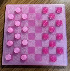 a close up of a plastic chess board on a wooden table with pink and purple buttons