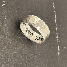 Elevate your style with this Hebrew ring featuring an intricate hammered sterling silver design. Engraved with a secret message from the Bible verse "God bless you and keep you" - "יברכך השם וישמרך" this unique piece exudes elegance and meaning. Perfect for a Jewish wedding band or a meaningful gift. This stunning sterling silver ring is more than just jewelry - it holds the powerful message "This too Shall Pass" from the Song of Solomon. The hammered design adds a touch of uniqueness and charm, making it a meaningful and stylish accessory for any occasion. Embrace tradition with a modern twist with this Hebrew ring crafted from sterling silver. Adorned with a touching Bible verse, "I Am My Beloved," this piece symbolizes love and commitment. Perfect for a Jewish wedding band or as a thoug Sterling Silver Engraved Ring For Anniversary, Symbolic Engraved Anniversary Ring, Thick Band Sterling Silver Engraved Ring For Anniversary, Silver Engraved Ring With Stamped Detail For Promise, Stamped White Gold Jewelry For Promise, Anniversary Sterling Silver Engraved Ring With Thick Band, Hammered Round Band Jewelry For Anniversary, Anniversary Engraved White Gold Ring Stamped, Anniversary Jewelry With Wide Band And Stamped Details