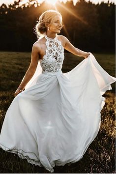 a woman in a white dress is walking through the grass with her hands on her hips