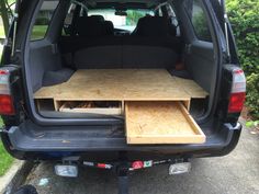 the back end of a van with an open hatchback and wooden trays in it