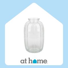 a clear glass vase sitting on top of a blue and white sign that says at home