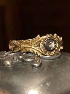 a close up of a gold ring on top of a metal object with a diamond in the center