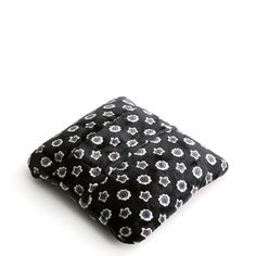 a black and white flowered square pillow on a white surface with the back side facing up