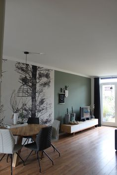 a living room with wood flooring and a tree painted on the wall behind it