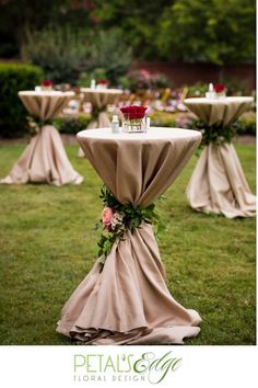 an outdoor setting with tables and chairs covered in burlock, flowers and greenery