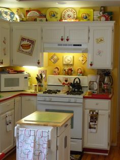 a kitchen with yellow walls and white cabinets has pictures on the wall above the stove