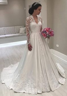 a woman in a white wedding dress holding a pink bouquet and posing for the camera