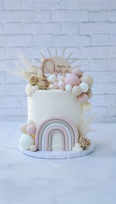 a white cake with pink and gold decorations on it's top, sitting on a table