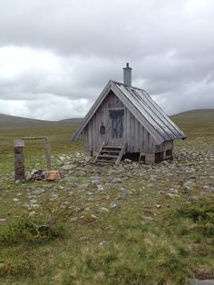 an old wooden cabin in the middle of nowhere with rocks and grass on the ground