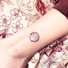 a small seashell tattoo on the wrist