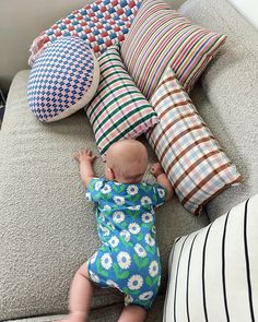 a baby is playing with pillows on the couch