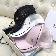 three hats are sitting in a box on a white couch next to a black and pink hat