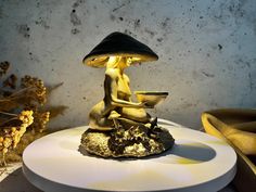 a gold statue sitting on top of a white plate next to a vase and mushrooms