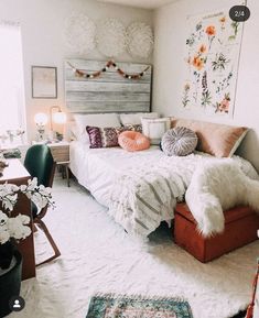 a bedroom decorated in white and pink with flowers on the wall, rugs and bedding