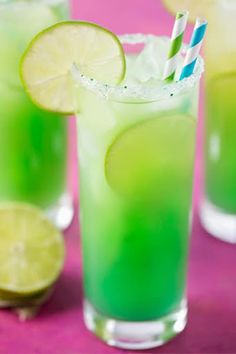 two glasses filled with green liquid and lime slices on the rim, next to each other