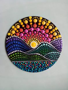 a colorful painting on a white surface with dots in the shape of mountains and hills