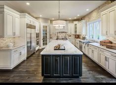 an image of a kitchen with white cabinets and black island in the foreground, on instagram