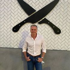 a man standing in front of a wall with two large knives on it's face