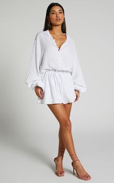 Turn heads in the Laylani Playsuit - V Neck Puff Sleeve In White. This playful and flirty playsuit is perfect for any casual occasion, with its A line shape and white cotton fabric that's both comfortable and chic. The v neck adds a touch of femininity, while the puff sleeves give it a trendy edge. Whether you're dressing up for a night out or keeping it cozy during winter, this long sleeve playsuit will have you looking effortlessly stylish wherever you go. So why wait? Go ahead and add this mu Summer V-neck Jumpsuit For Daywear, White Mini Length Jumpsuits And Rompers For Vacation, White Mini Length Summer Jumpsuit, White Summer Mini Jumpsuits And Rompers, White Mini Length Jumpsuits For Summer, White Mini Length Jumpsuits And Rompers For Summer, White Mini Jumpsuits And Rompers For Summer, White Mini Length Jumpsuits For Beach, White V-neck Jumpsuits For Daywear