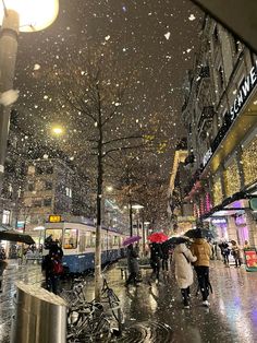 people are walking in the rain with umbrellas on a city street at night time