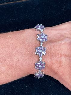 Sterling silver bezel set oval shape  genuine purple amethyst set in a flower pattern with round cubic zirconias set in between each flower and center of each flower.  This bracelet measures 7.5 inches in length with a box and tongue clasp and figure 8 safety. Super whimsical and fun to wear. Nice and smooth edges so it won't catch on anything. Rhodium plated so it will not oxidize.  20.07 grams Amethyst Set, Cubic Zirconia Bracelet, Valley View, Figure 8, Smooth Edges, Sterling Silver Flowers, Silver Flowers, Purple Amethyst, Chain Link Bracelet