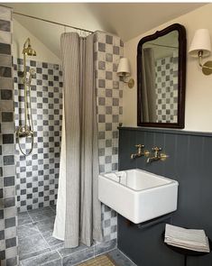 a bathroom with black and white checkered tiles on the walls, shower curtain, sink and mirror