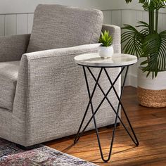 a living room with a chair, table and potted plant on the floor next to it