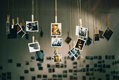 black and white photo hanging from strings with pictures on them in front of a wall