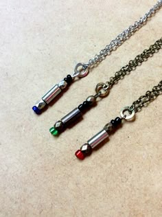 three necklaces with different colored beads hanging from them on a counter top next to each other