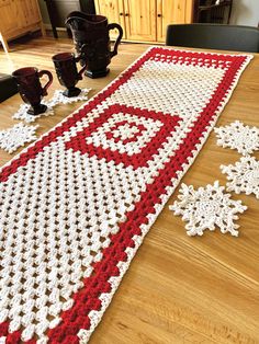 a crocheted table runner with red and white snowflakes on the edge