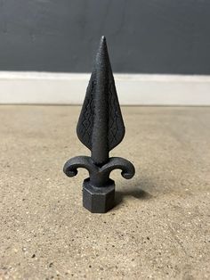 a small black object sitting on top of a cement floor next to a gray wall