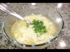 a glass bowl filled with soup and garnished with chopped green onions on the side