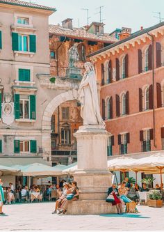 people are sitting on benches in the middle of an old town square with tall buildings