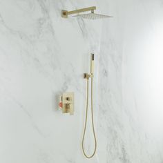 a shower head and hand shower in a white bathroom with marbled walls, gold faucet, and brass fixtures