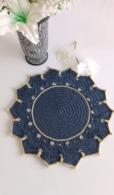 a crocheted doily sits next to a vase with white flowers in it